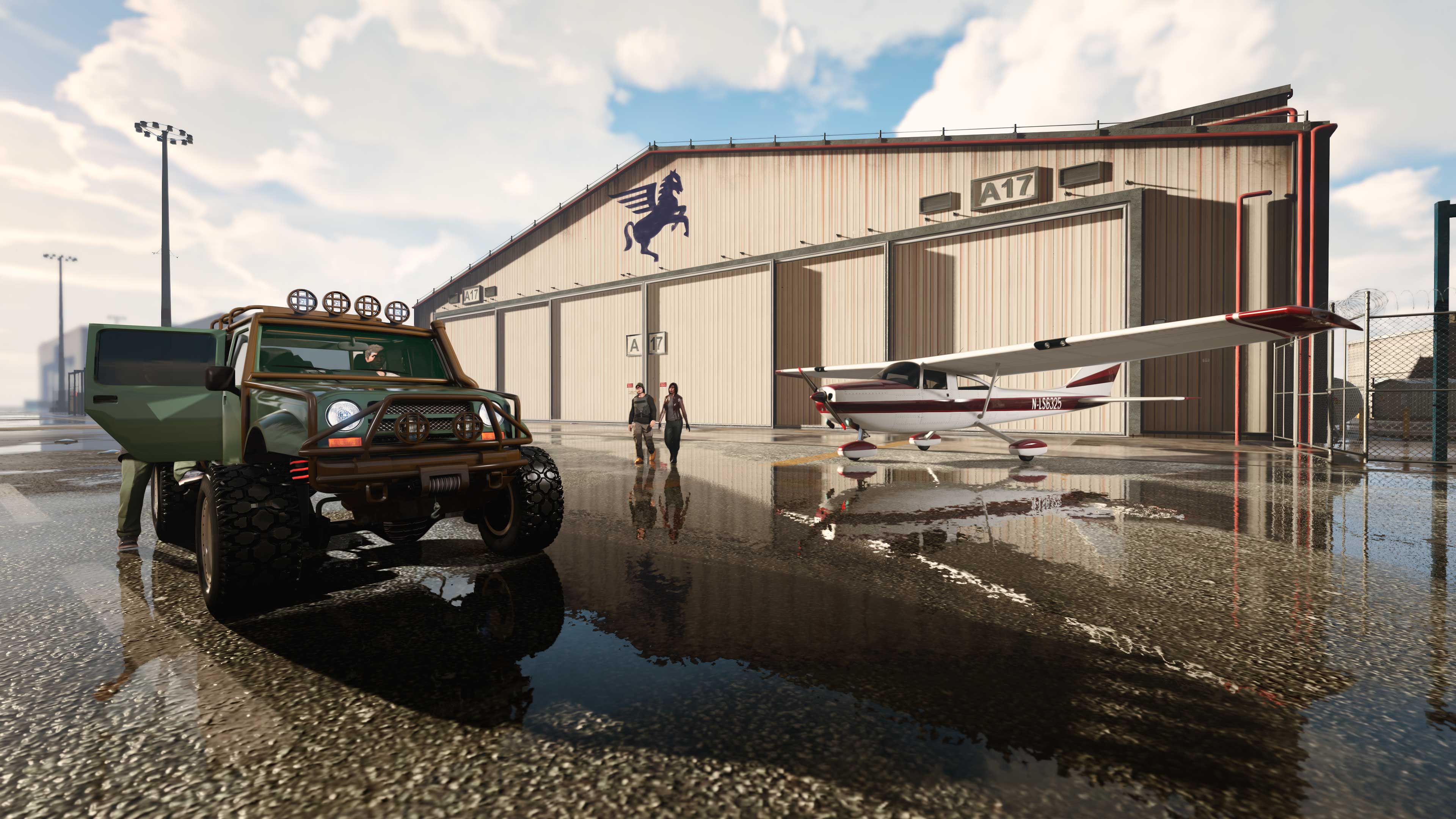 Imagem de um carro off-road e um avião do lado de fora de um hangar.